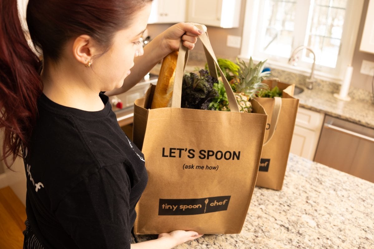 A Tiny Spoon chef unpacking a “Let’s Spoon” grocery tote in a client’s kitchen